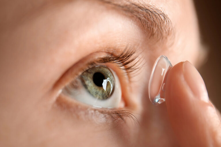 Close-up of a woman applying a soft contact lens to her dry eye